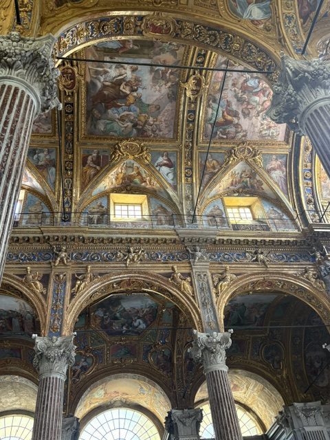 Frescoed vault and dome paintings above Corinthian columns and arched windows
