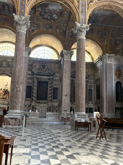 Church side aisle, checkerboard marble floor, arcaded chapels, wooden lecterns and tables
