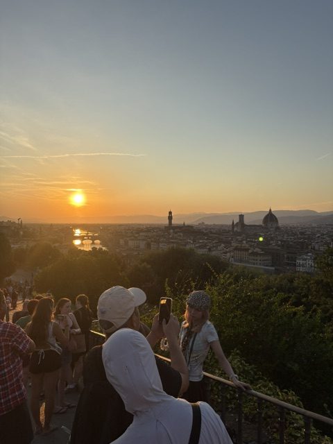 Sunset over Florence from a hilltop terrace, crowd silhouetted along the railing