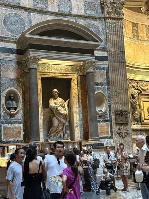 Pantheon interior, marble columns and colored stone niche holding a statue, gilded decoration, tourists in front