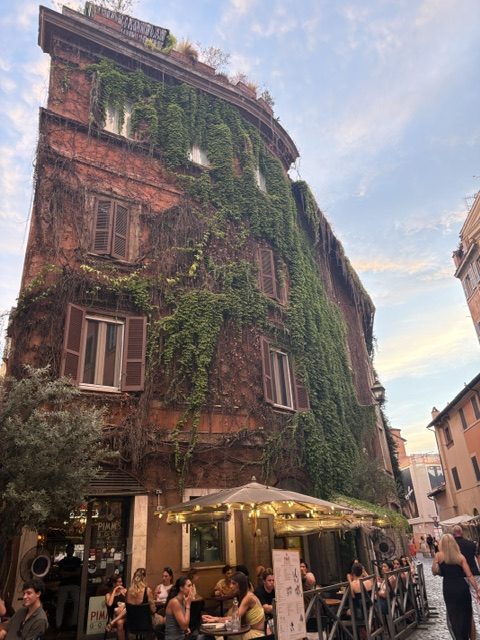Ochre corner building smothered in ivy at dusk, cafe awning and outdoor diners at street level